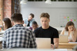 © fizkes - Serious businessman focused on laptop, man using pc sitting at shared office desk, busy developer programmer concentrated on work in co-working space, trader looking at screen monitoring stock online