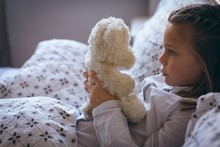Girl Holding Teddy Bear On Bed