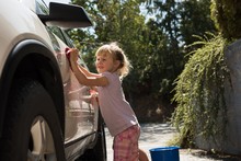 Girl Washing A Car Outside The Garage On A Sunny Day