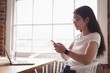 © Wavebreak Media - Young businesswoman using smartphone while sitting in office