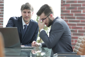 Two businessmen working together using laptop on business meeting in office