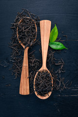 Wall Mural - Dry black tea. On a wooden background. Top view. Copy space.