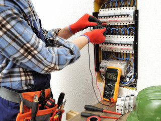 Wall Mural - Young electrician technician at work on a electrical panel with protective gloves