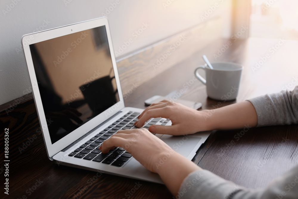 Young woman working on laptop in cafe, closeup