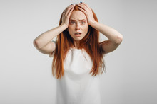 Emotional Redhead Girl On White Background With Fear, Open Mouth And Hands On Head