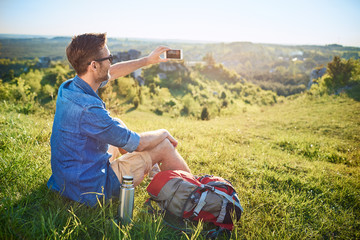 Wall Mural - Man taking photo of beautiful view during hiking in the mountains