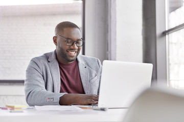 professional male economist searches needed information on portable computer, happy to recieve high 