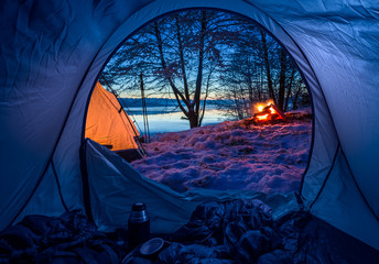 Wall Mural - camp by the lake with campfire in winter at dusk