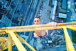 Rock climber hanging on jib of construction crane with one hand
