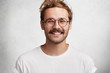 © WHstudio Leushin N - Portrait of cheerful attractive young man with stylish hairdo, pleasant pleased broad smile, dressed casually, has happy expression after realizing positive news, poses against white background.