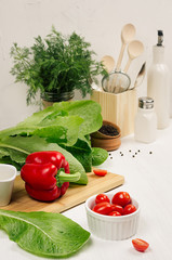 Wall Mural - Healthy vegeterian ingredients for spring fresh green salad and kitchenware in white elegant kitchen interior. Spring vitamin dieting food.