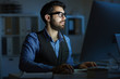 © pressmaster - Businessman looking at computer monitor in office while working in the dark