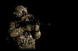 Army soldier in Combat Uniform with assault rifle, combat helmet and night vision device. Studio shot, dark background