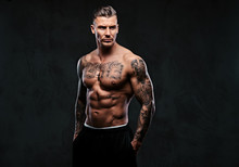 A Muscular Tattooed Man On A Dark Background.