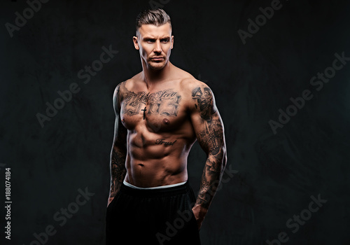 Fotografía A muscular tattooed man on a dark background.
