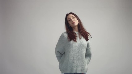 Wall Mural - pretty young spanish woman posing in studia looking at camera and smiling wearing grey owersized sweater