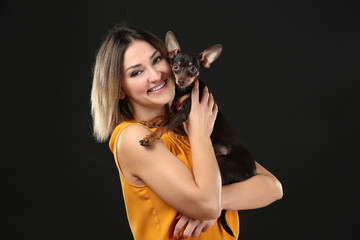 Young beautiful smiling woman with cute dog on black background