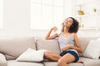 © Prostock-studio - Happy young woman in headphones on beige couch