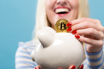 Wall Mural - Woman with bitcoin and a piggy bank on ablue background