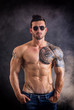 © theartofphoto - Handsome shirtless muscular man with jeans, standing and wearing sunglasses, on dark smoky background in studio shot