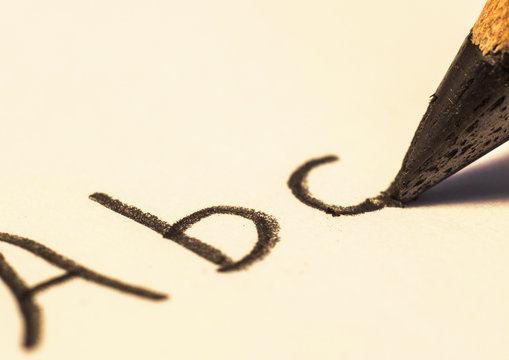alphabet letter on paper and black pencil