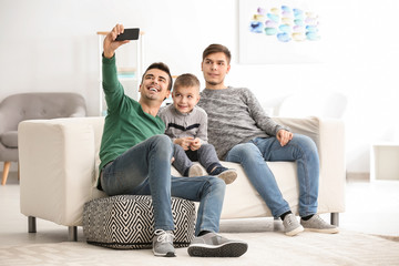 Wall Mural - Male gay couple with adopted boy taking selfie at home