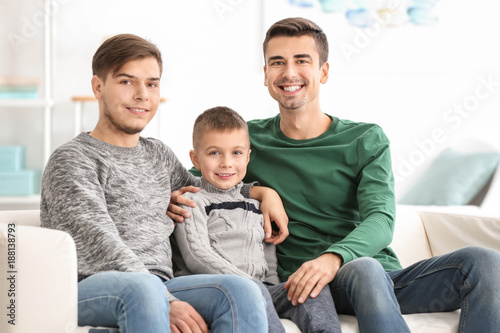 Male Gay Couple With Adopted Boy Sitting On Sofa At Home