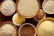 Various groats, cereals. Different types of groats in bowls on a wooden background, top view, close up. Healthy nutrition food