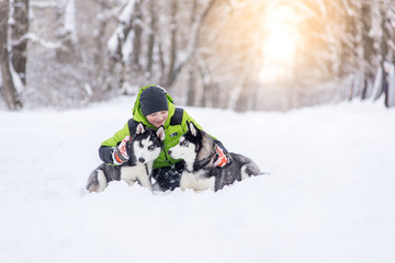 boy playing with his dogs husky playing in the park in winter on snow