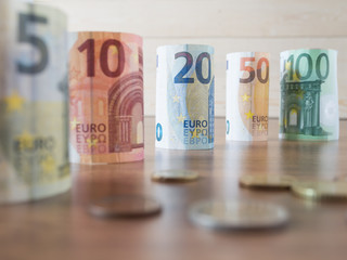 euro banknotes with wood background.Rolls of Euro banknotes and serveral coins.