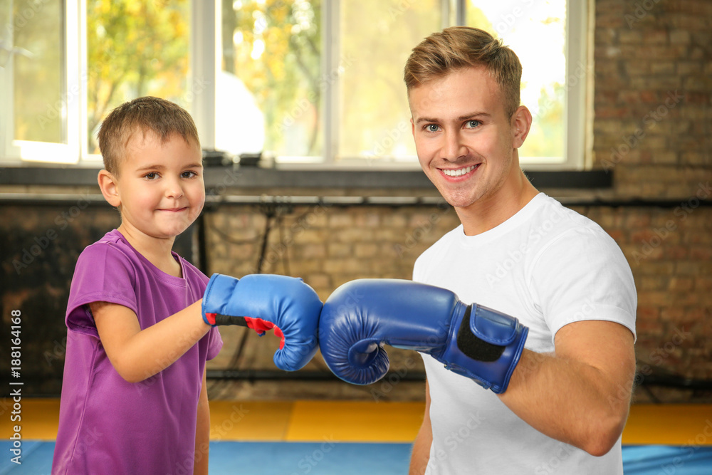 Little boy with trainer in boxing gloves indoors