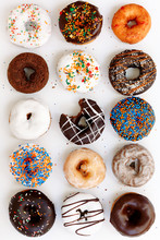 Assorted Donuts With Chocolate Frosted, White Glazed And Sprinkled Donuts On White Background, Top View