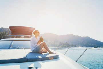 Wall Mural - woman enjoying sunset trip onboard of luxuious yacht, luxury sea cruise travel on the boat