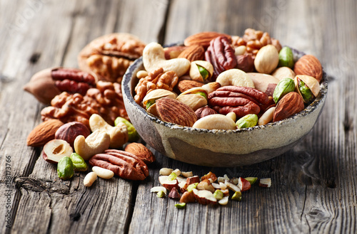 Fotografía Mixed and cut nuts on a wooden background