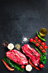 Wall Mural - Raw meat, beef steak on a stone cutting board with rosemary, spices, salt, oil, cherry tomatoes, hot pepper and herbs