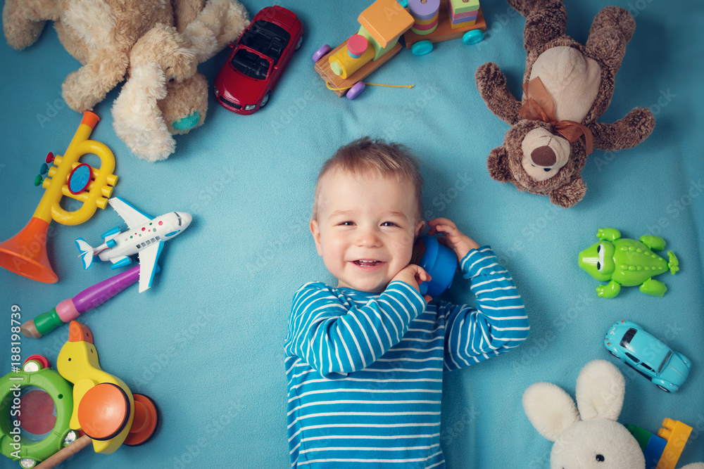 Happy one year old boy lying with many plush toys - obrazy, fototapety, plakaty 