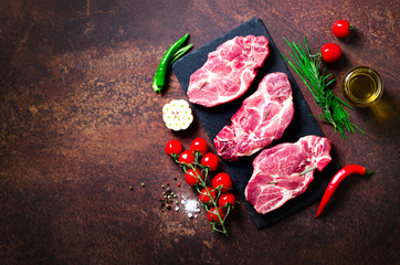 Wall Mural - Raw meat, beef steak on a stone cutting board with rosemary, spices, salt, oil, cherry tomatoes, hot pepper and herbs