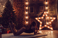 Sexy Woman Lying On The Floor Against The Backdrop Of The Christmas Tree.