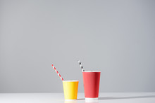 Red And Yellow Paper Cups With Drinking Straws On Grey