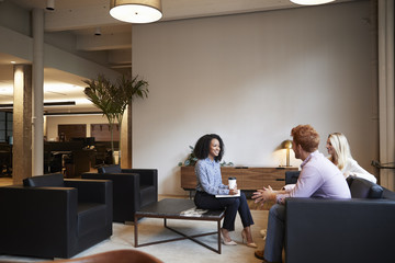 Wall Mural - Three colleagues at a casual work meeting in a lounge area