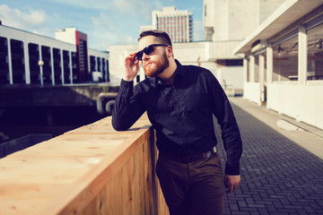 Wall Mural - Young handsome man in stylish black clothes and sunglasses.