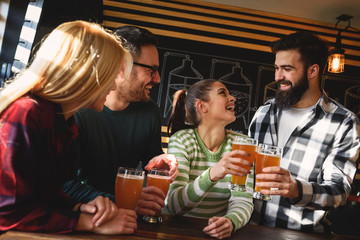 Wall Mural - Smiling young people drinking craft beer in pub