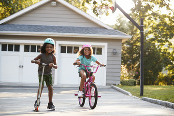 Wall Mural - Sister With Brother Riding Scooter And Bike On Driveway At Home