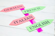 © 976photo - Learning Foreign Languages concept: German, English, Italian, French paper arrows on a light colored wooden background, close up, top view