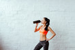 the sports girl the brunette in an orange topic with a fitness shaker