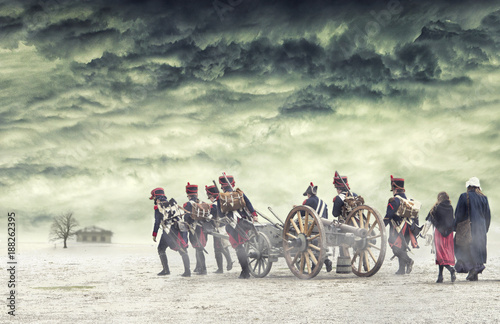 Fotografija Napoleonic soldiers and women marching and pulling a cannon in plain land, countryside with stormy clouds