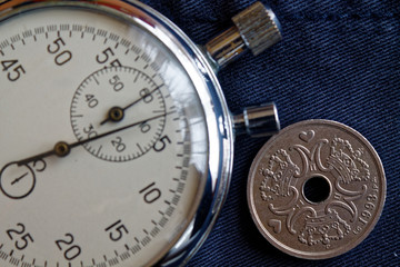 Denmark coin with a denomination of two crown (krone) (back side) and stopwatch on dark blue jeans backdrop - business background