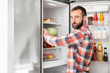 © Africa Studio - Handsome man choosing food in refrigerator at home