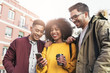 © santypan - Group of happy friends using the mobile in the street.