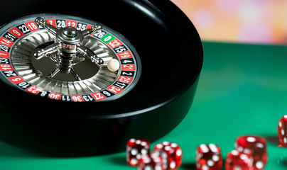 High contrast image of casino roulette and poker chips on bokeh background.